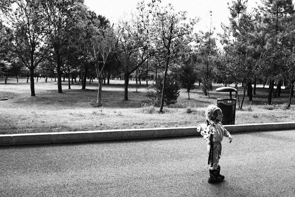 Foto en escala de grises de un niño caminando por la carretera