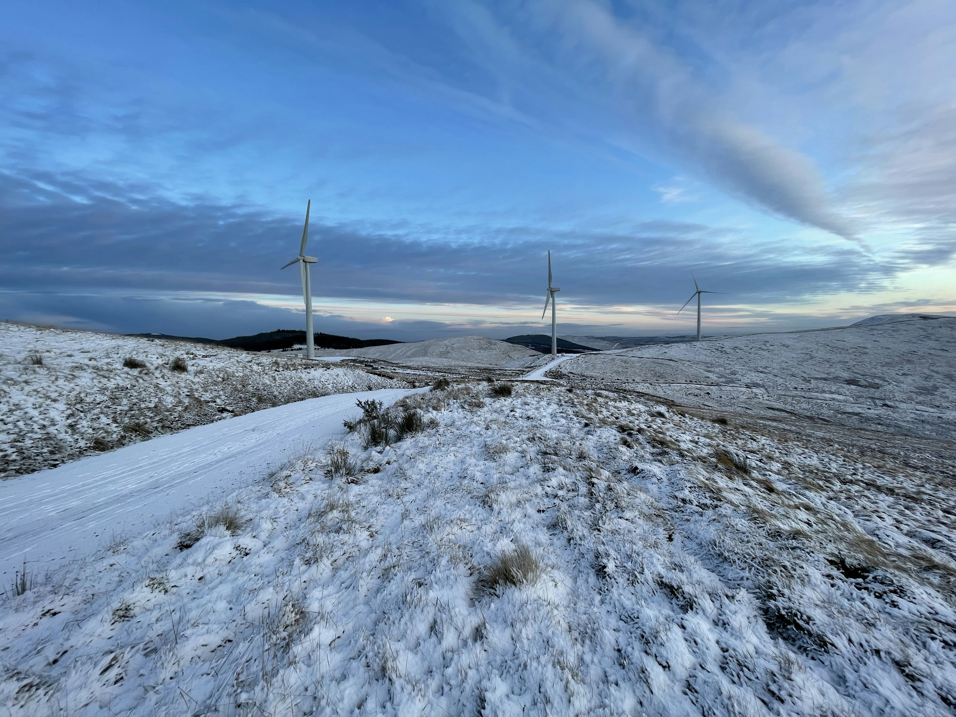 white wind turbines on snow covered ground under blue sky during daytime