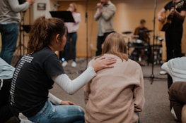 woman in black long sleeve shirt and blue denim jeans holding woman in beige sweater