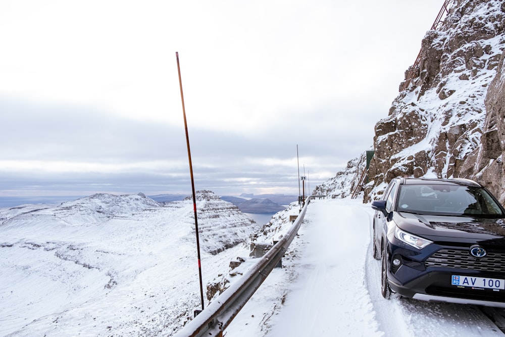 black car on road covered with snow during daytime