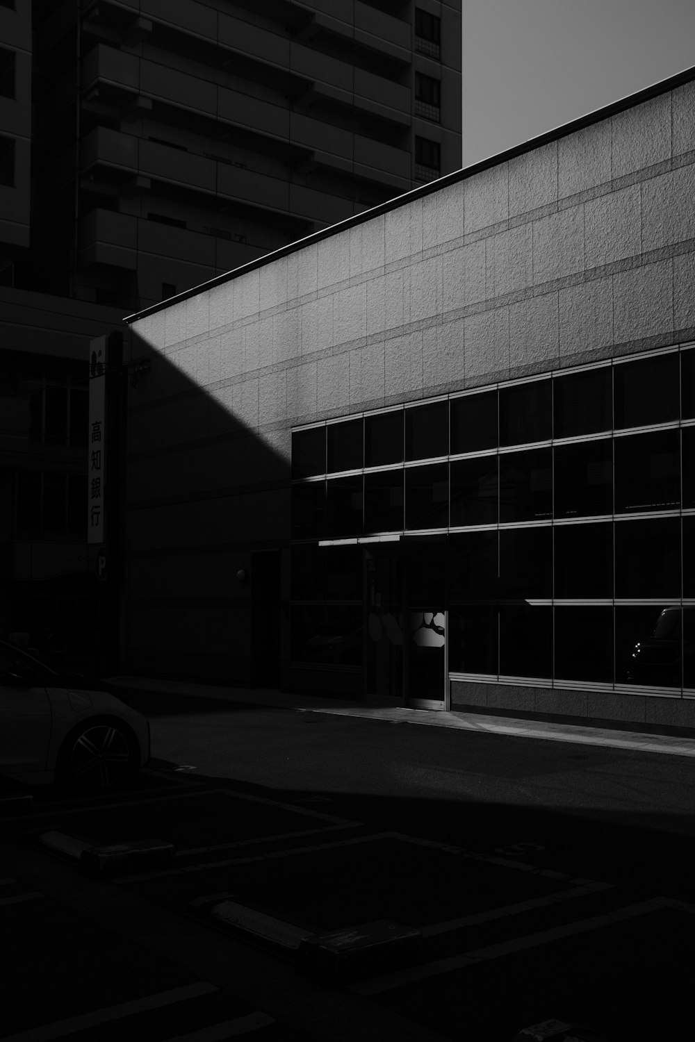 grayscale photo of a car parked in front of a building
