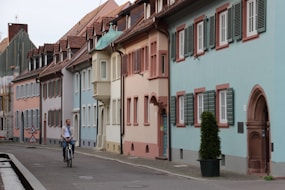 people walking on sidewalk near white and pink concrete building during daytime
