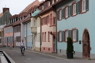 people walking on sidewalk near white and pink concrete building during daytime