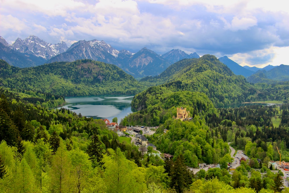 green trees and mountains near lake under blue sky during daytime