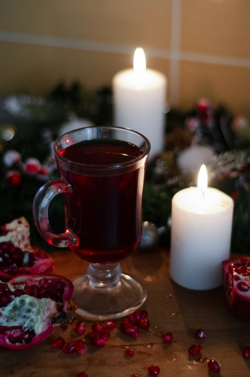 clear glass mug with red liquid beside white pillar candle