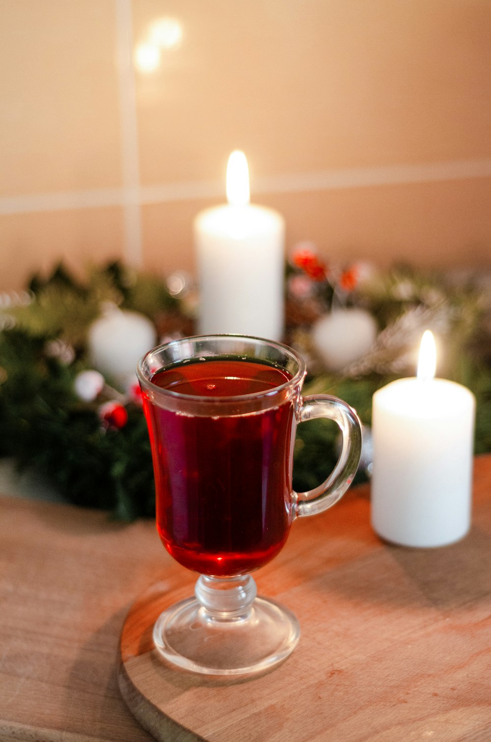 clear glass mug with red liquid beside white pillar candle