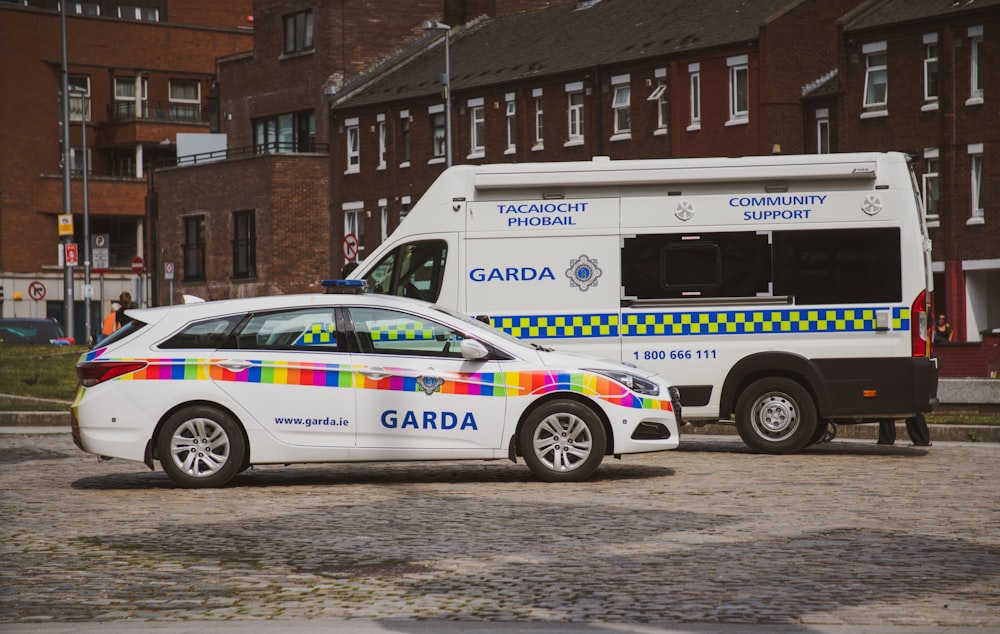 white and blue police van parked beside brown concrete building during daytime