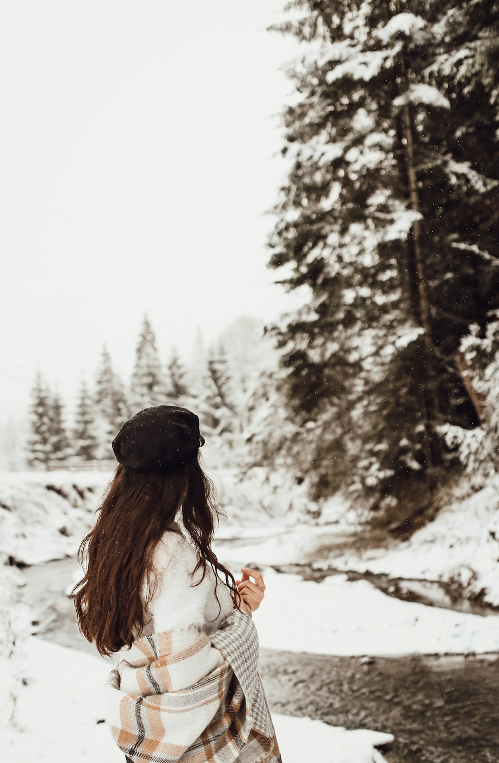 woman in white tank top and black knit cap standing on snow covered ground during daytime