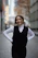 Smiling woman wearing a stylish outfit from vesteviva, standing in a cozy urban setting.