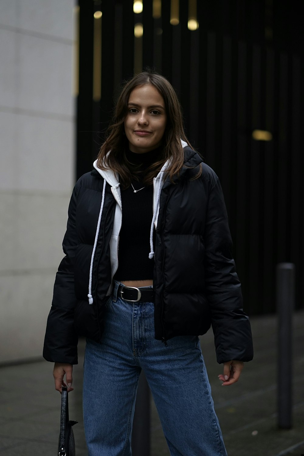 woman in black jacket standing near black wall