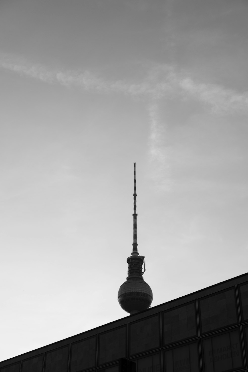 grayscale photo of tower under cloudy sky