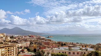 city buildings near sea under white clouds and blue sky during daytime