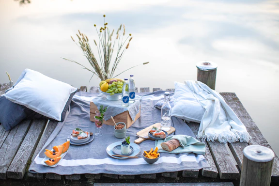 A serene coastal scene with a picnic setup featuring gourmet food and elegant tableware.
