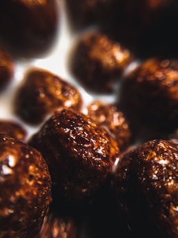 Close-up view of chocolate cereal balls in milk, highlighting their glossy texture and rich brown color.