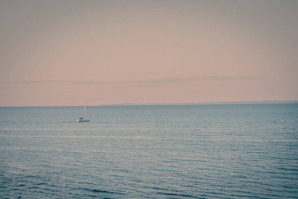 a lone sailboat in the middle of the ocean