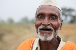 An elderly man smiling while a caregiver assists him with a morning walk in a garden