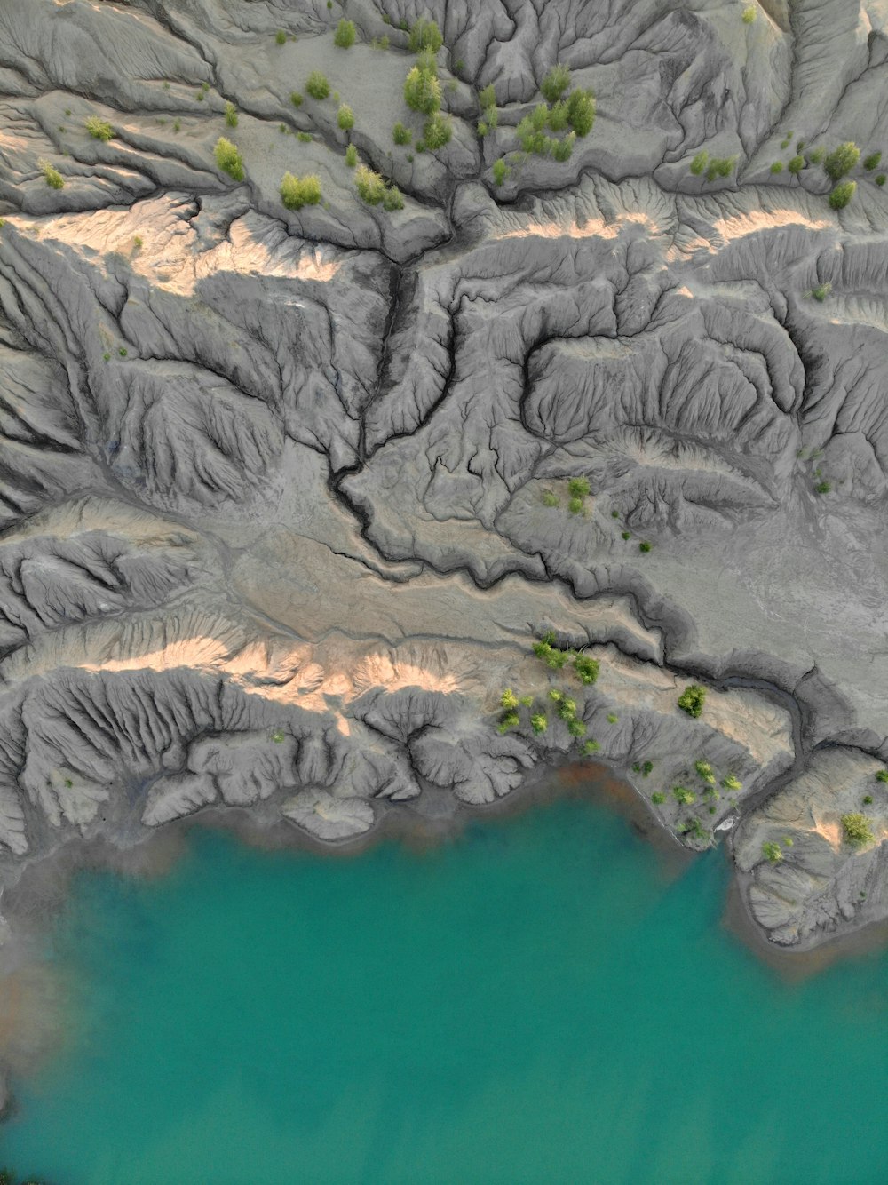 aerial view of gray rocky mountain beside green body of water during daytime