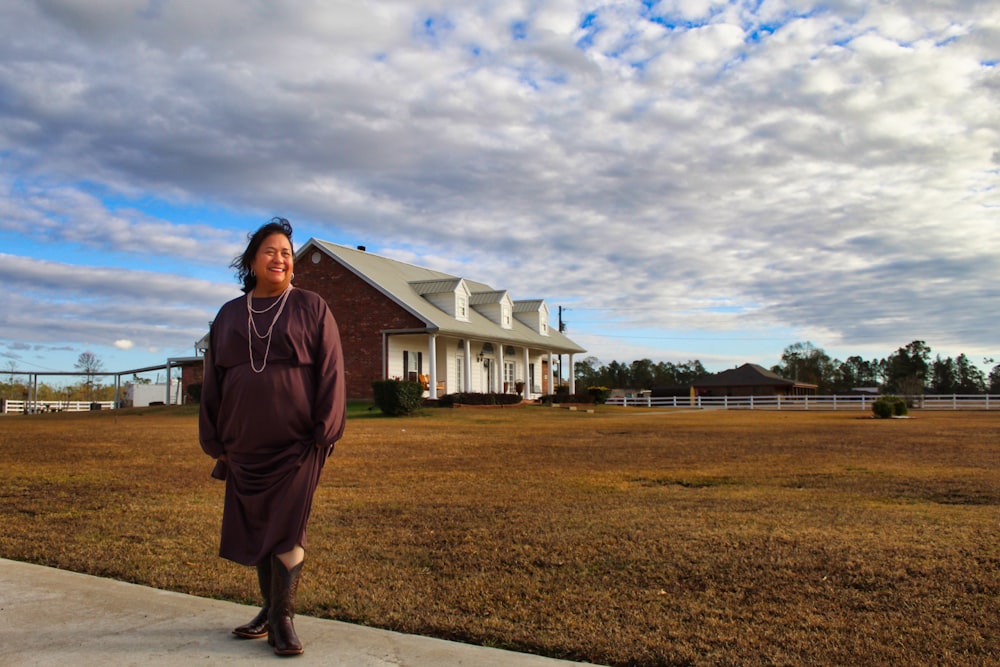 woman in red jacket standing on green grass field during daytime