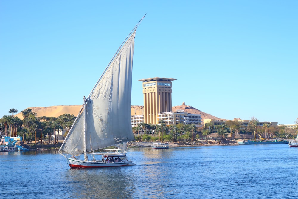 white sail boat on water near city buildings during daytime