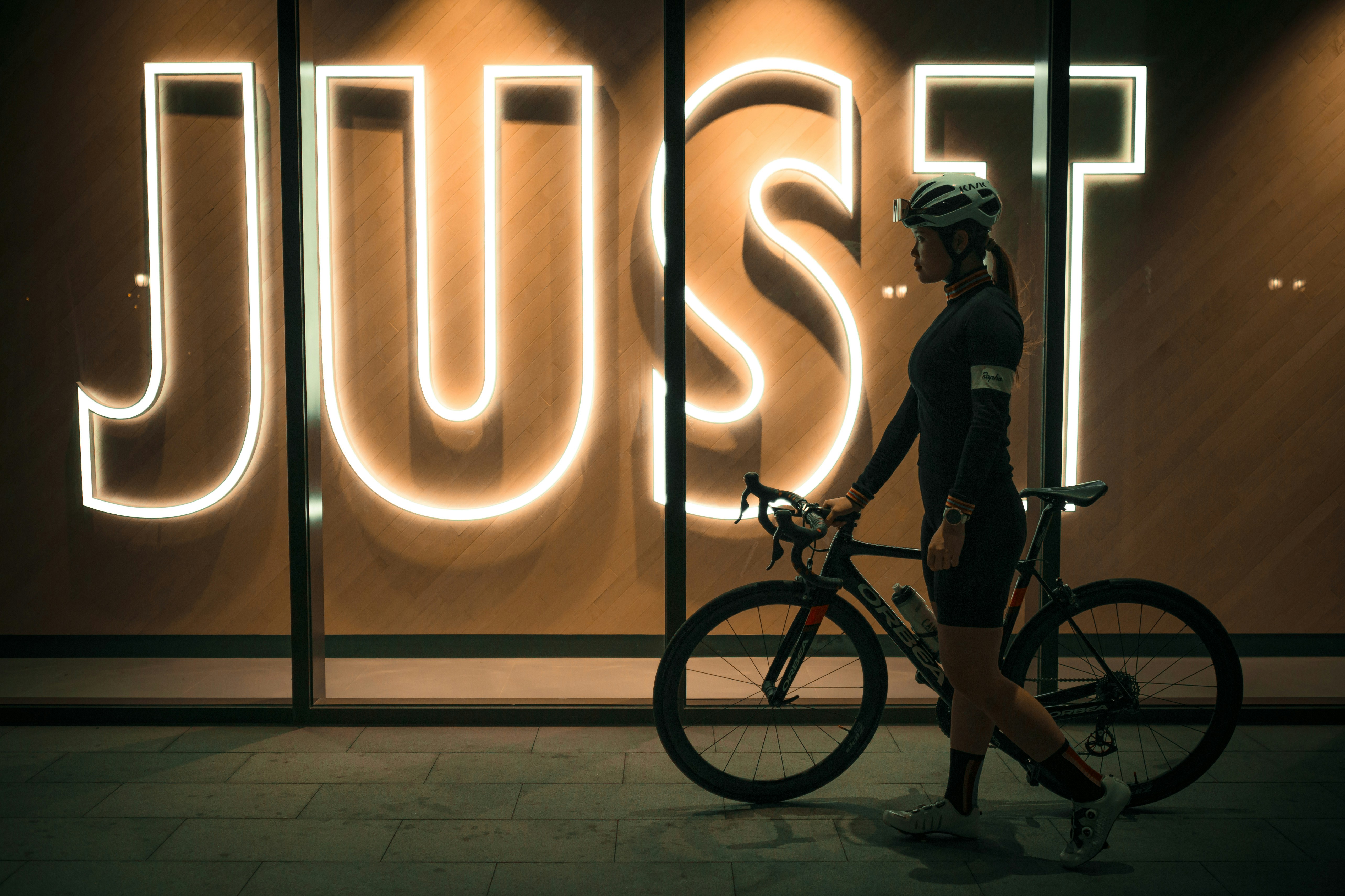 man in gray jacket and black pants standing beside black bicycle