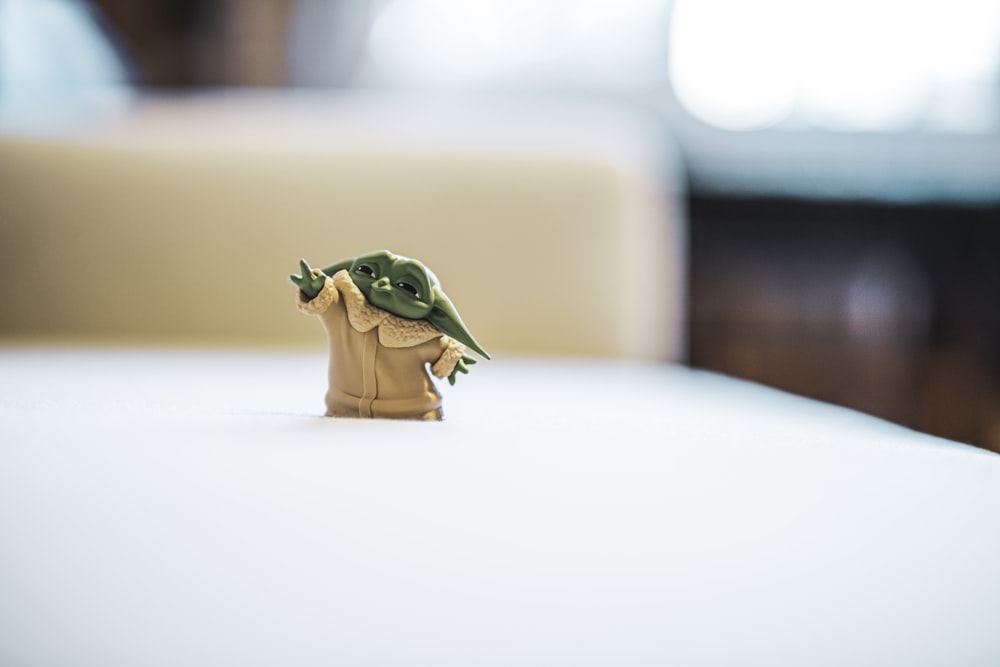 green frog figurine on white table