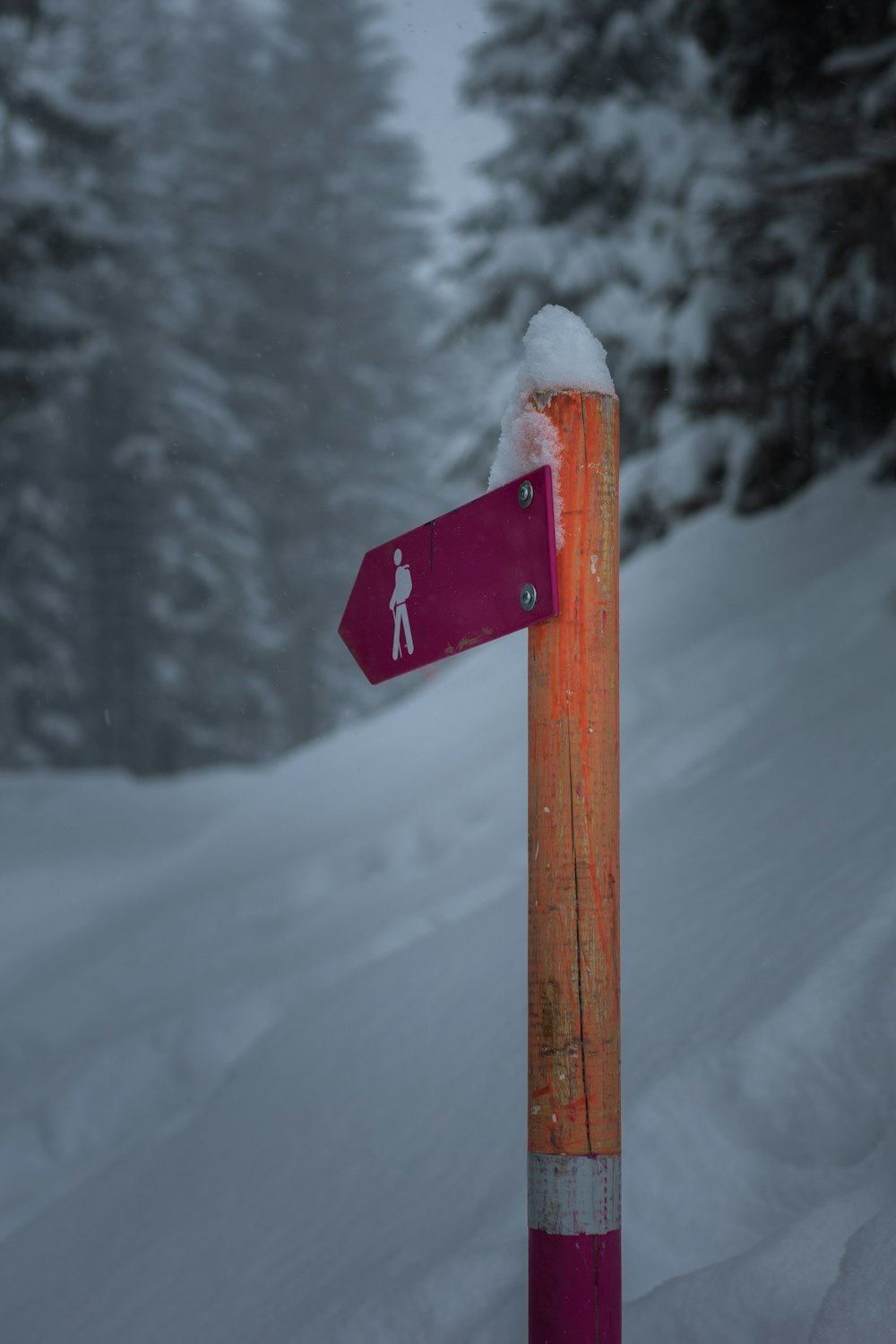 red and white wooden arrow sign on snow covered ground