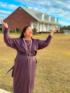 Fashionable woman in a purple dress posing outdoors with a joyful expression