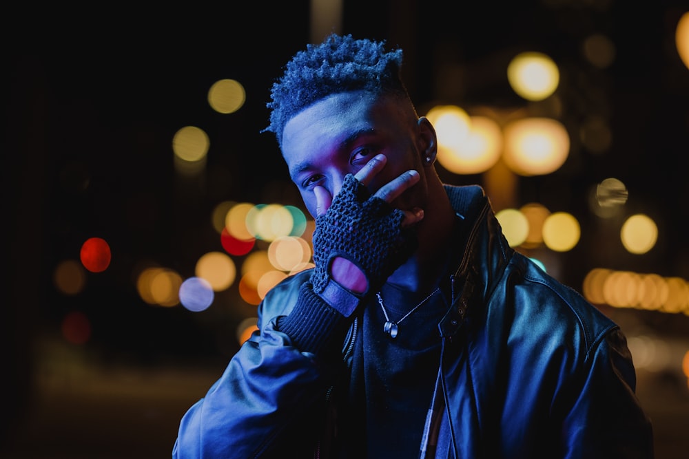 man in blue jacket covering his face with his hand