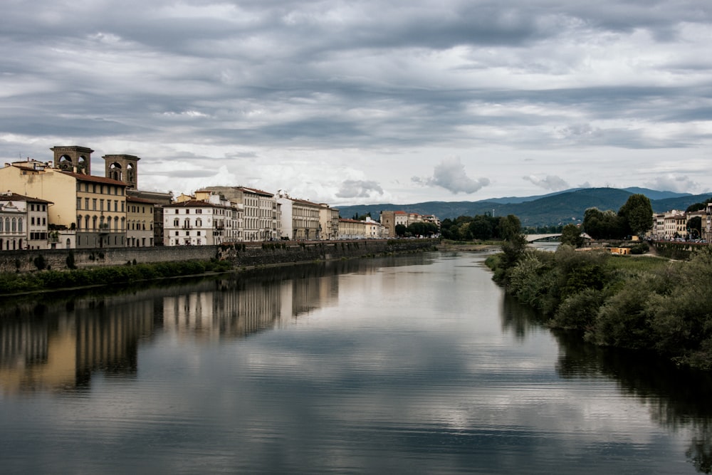 white and brown concrete building near body of water under cloudy sky during daytime