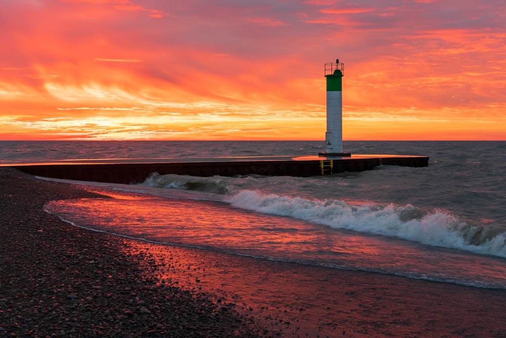 white and red lighthouse on seashore during sunset