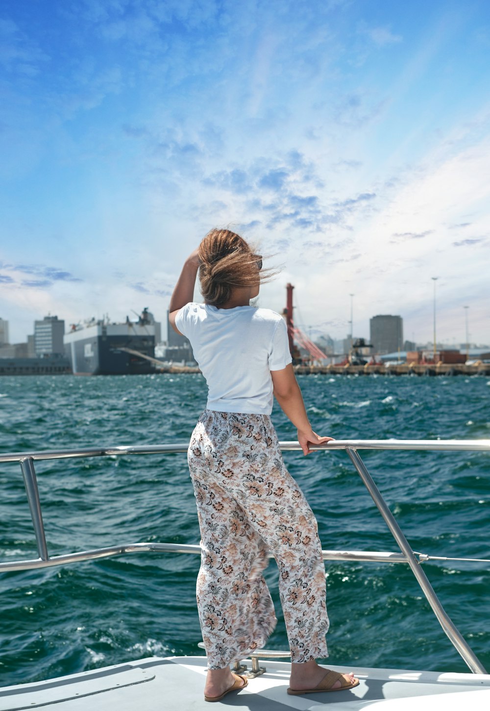 woman in white t-shirt and brown floral skirt standing on boat during daytime