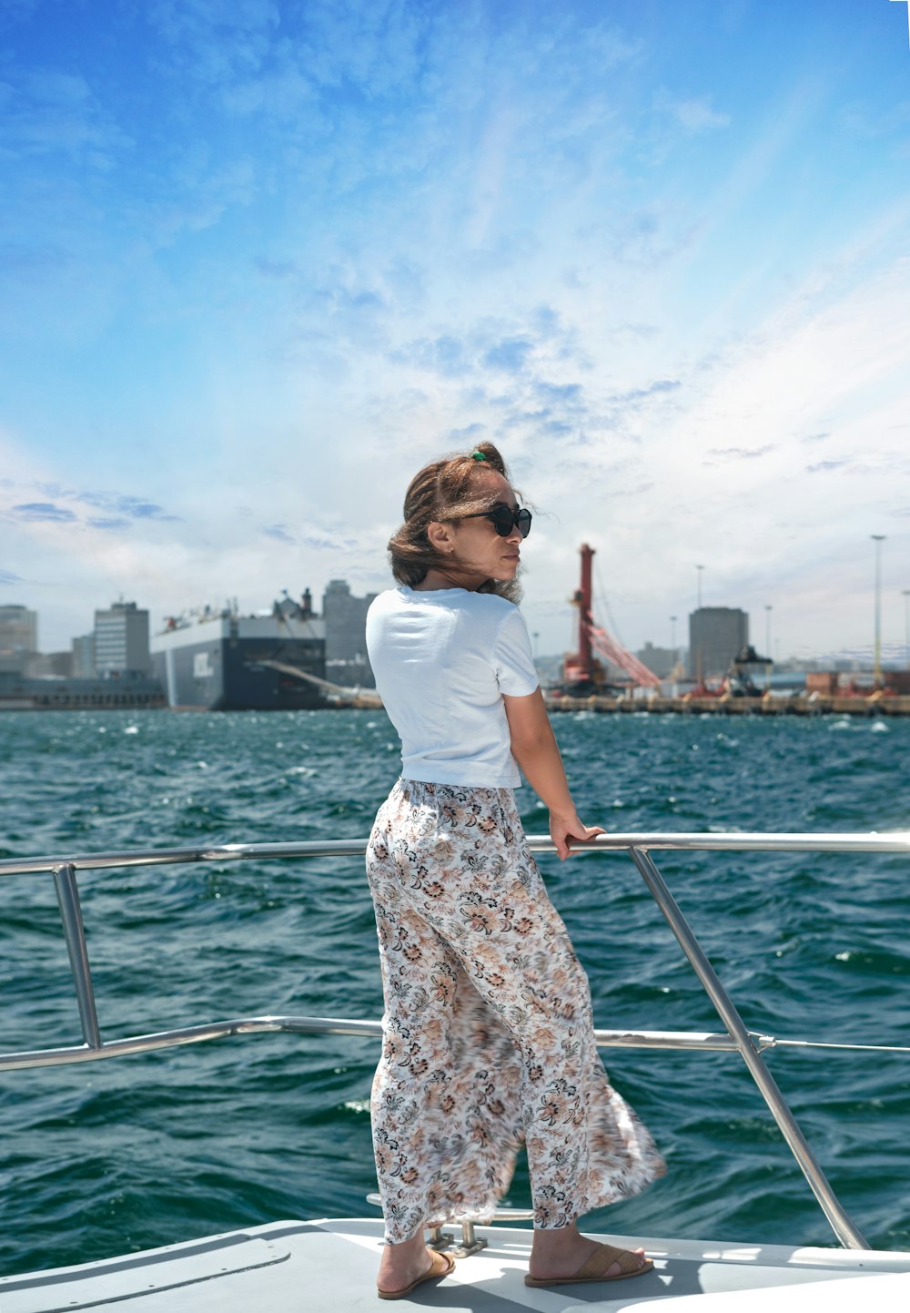 woman in white shirt and brown floral skirt standing on boat during daytime