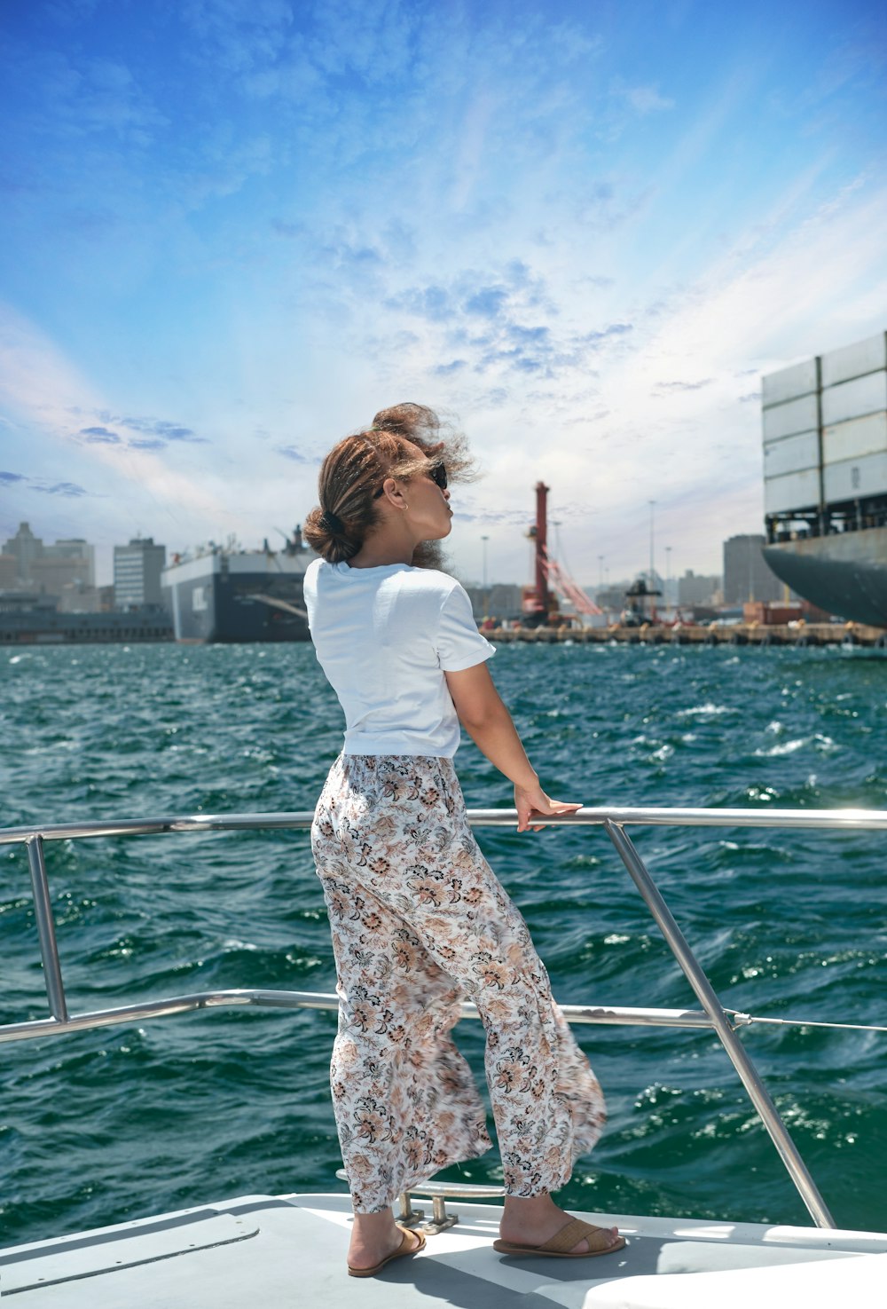 woman in white t-shirt and black and white floral skirt standing on boat during daytime