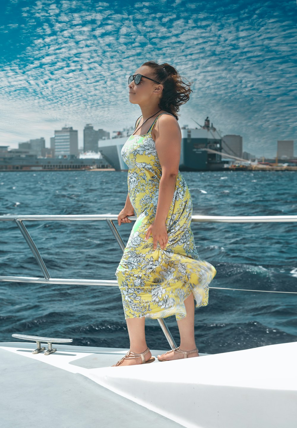 woman in yellow and white floral spaghetti strap dress standing on boat during daytime