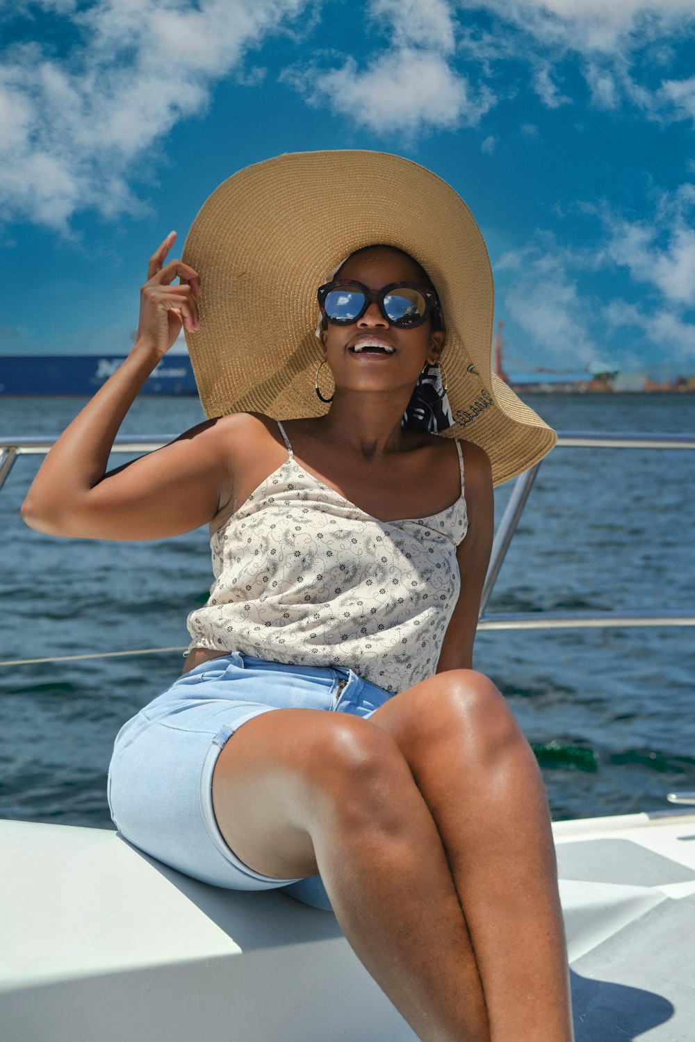 a woman in a hat and sunglasses sitting on a boat