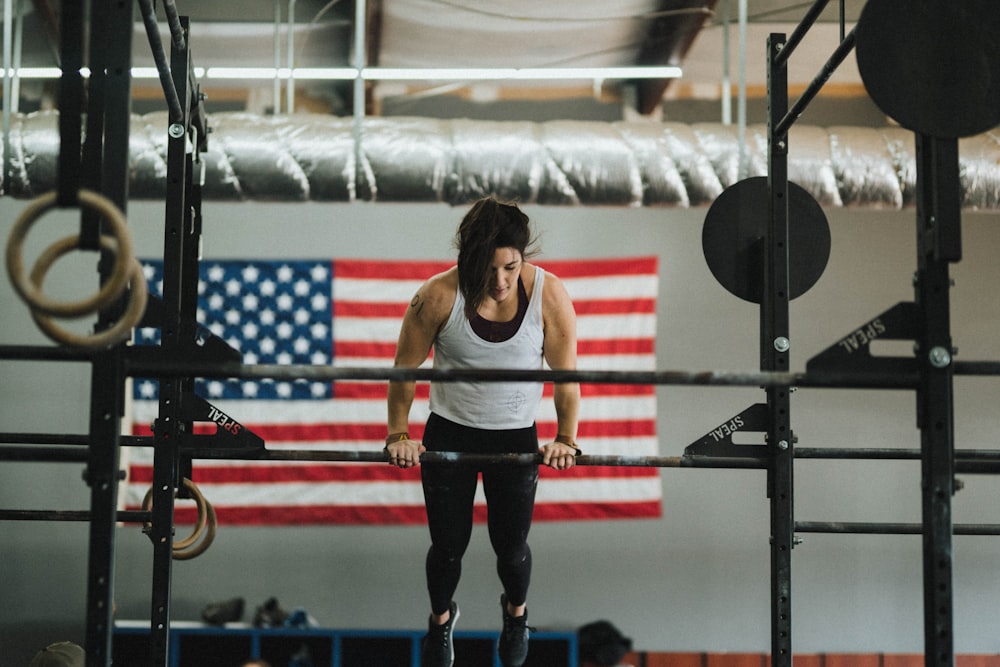 woman in gray tank top and black pants standing on red and black exercise equipment