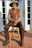 Stylish man in a straw hat standing confidently in a sunlit gym with western decor.