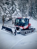 A Prinoth snow groomer smoothing a snowy mountain trail at sunrise.