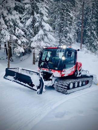 A Prinoth snow groomer smoothing a snowy mountain trail at sunrise.