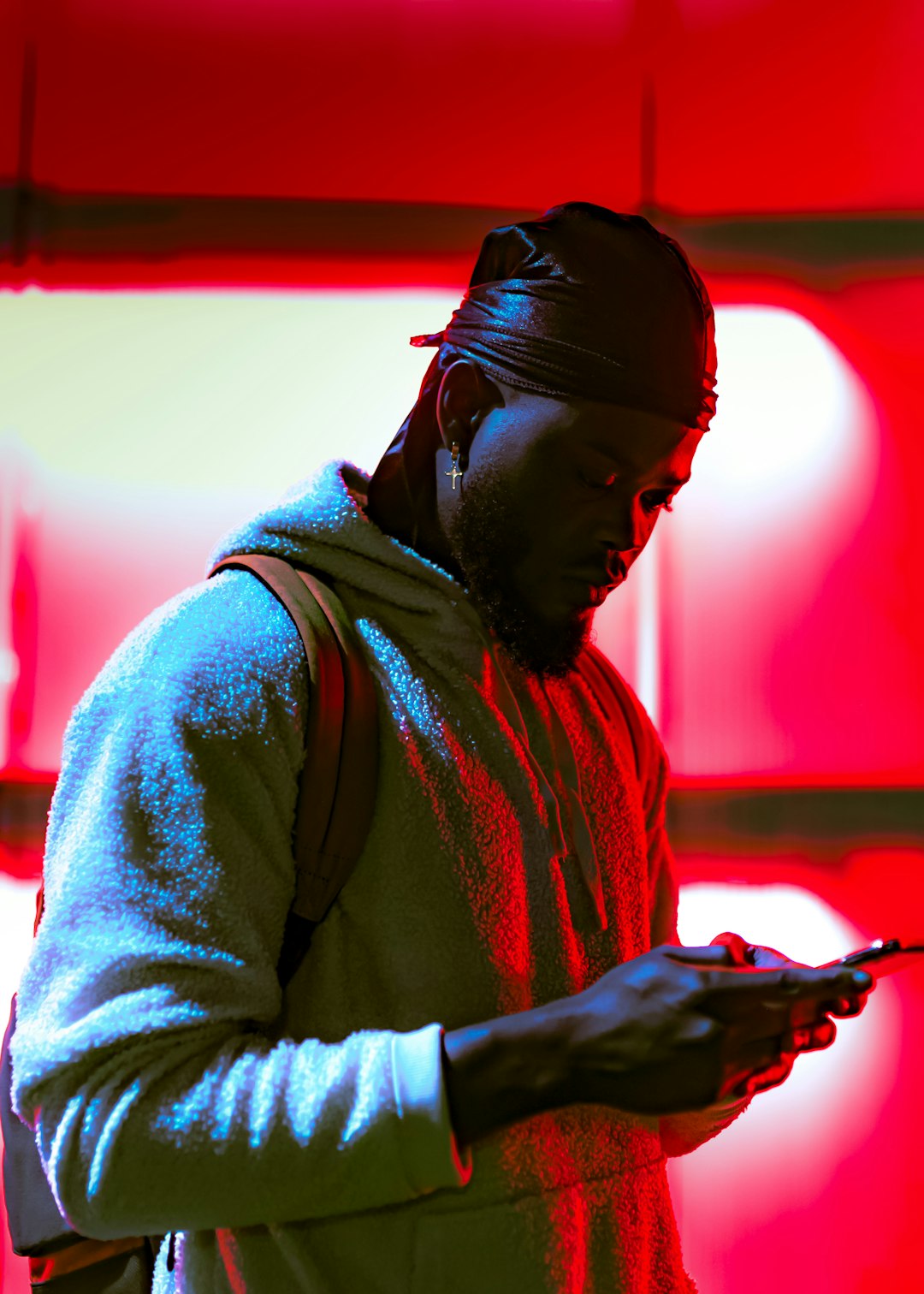 man in gray hoodie holding black smartphone