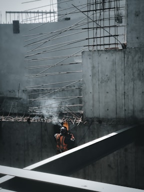 man in orange jacket sitting on the edge of a building