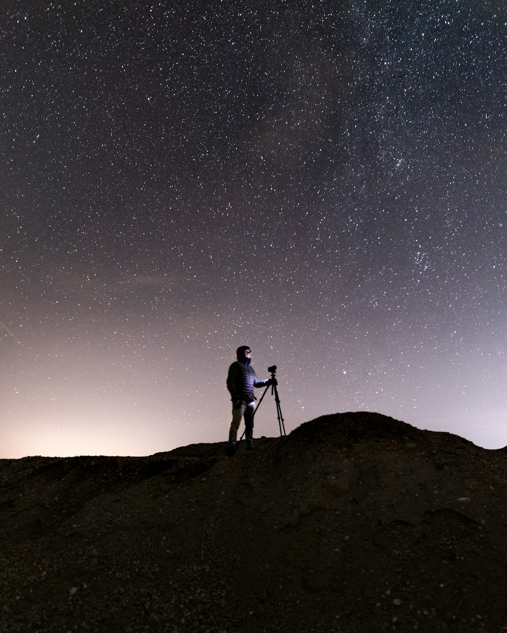 silhouette of man and woman standing on hill under starry night