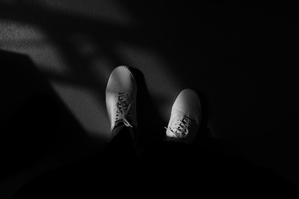 Foto en escala de grises de una persona con pantalones negros y zapatillas blancas