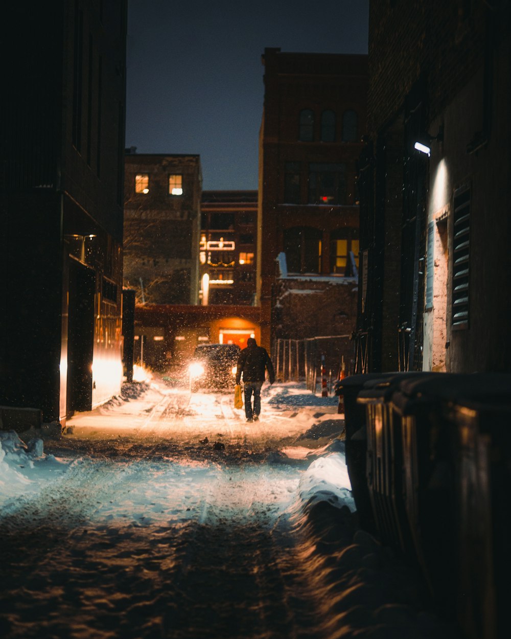 snow covered road between buildings during night time