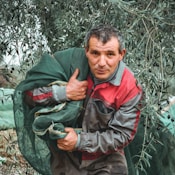 man in green jacket holding green plant