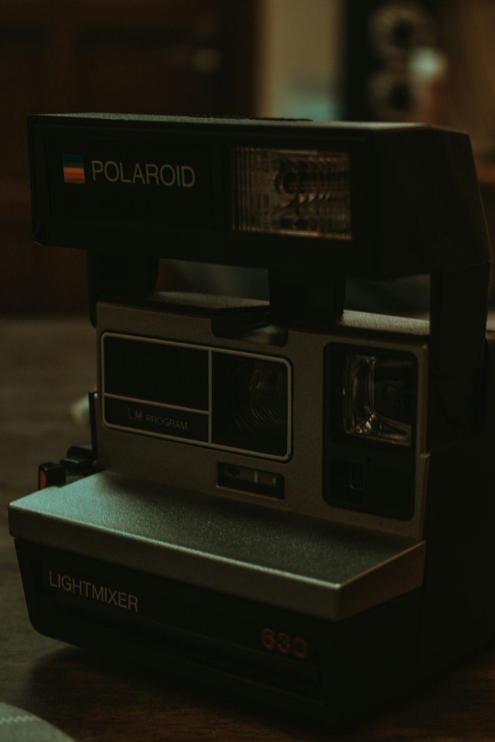black polaroid instant camera on brown wooden table