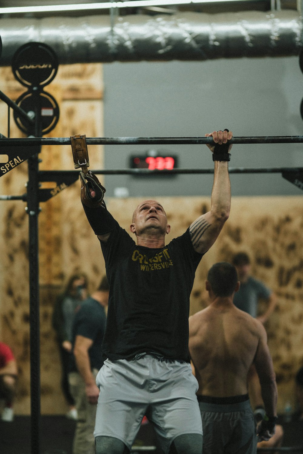 man in black crew neck t-shirt and gray shorts holding black metal bar