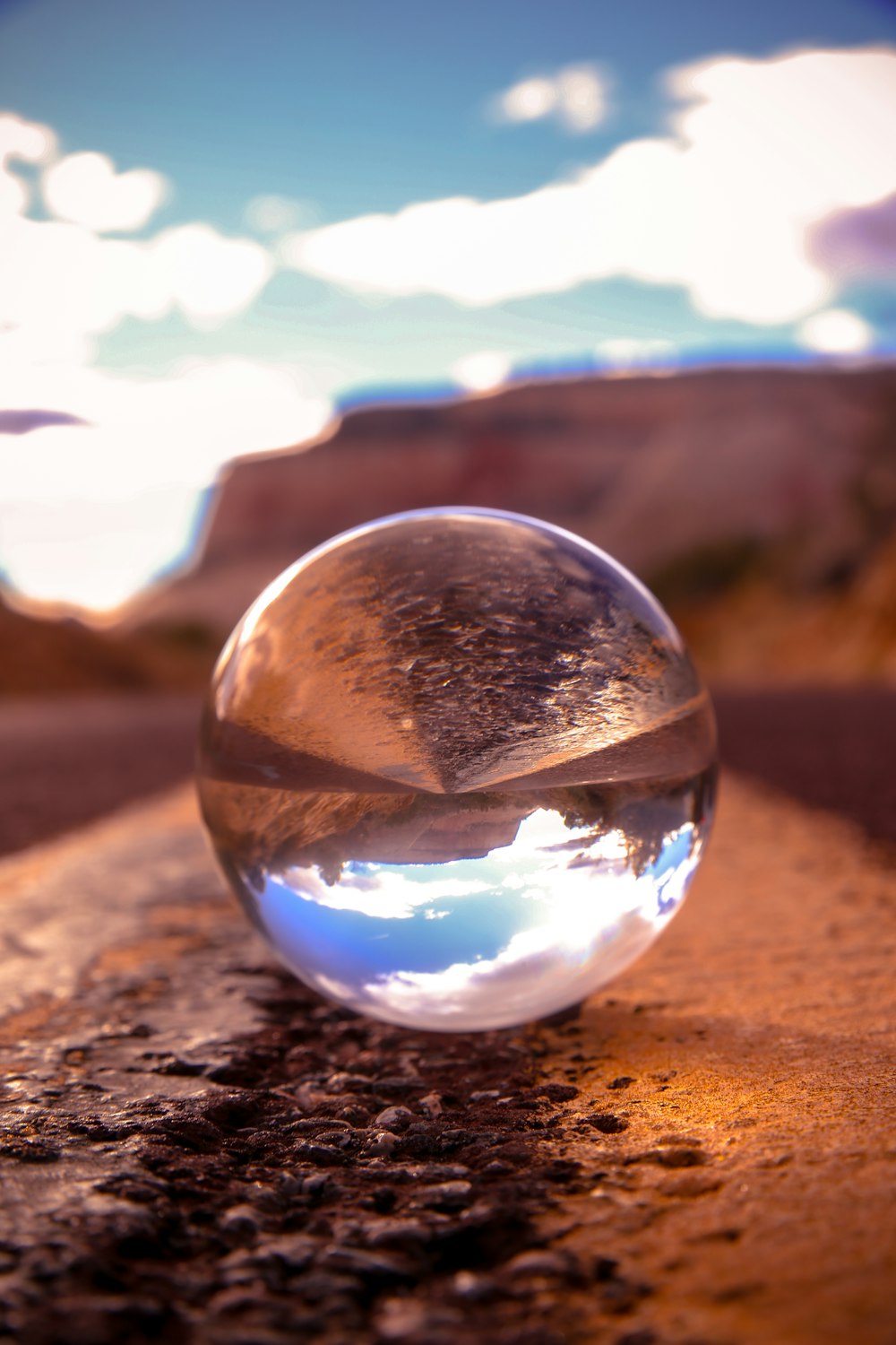 bola de vidro transparente na areia marrom durante o dia