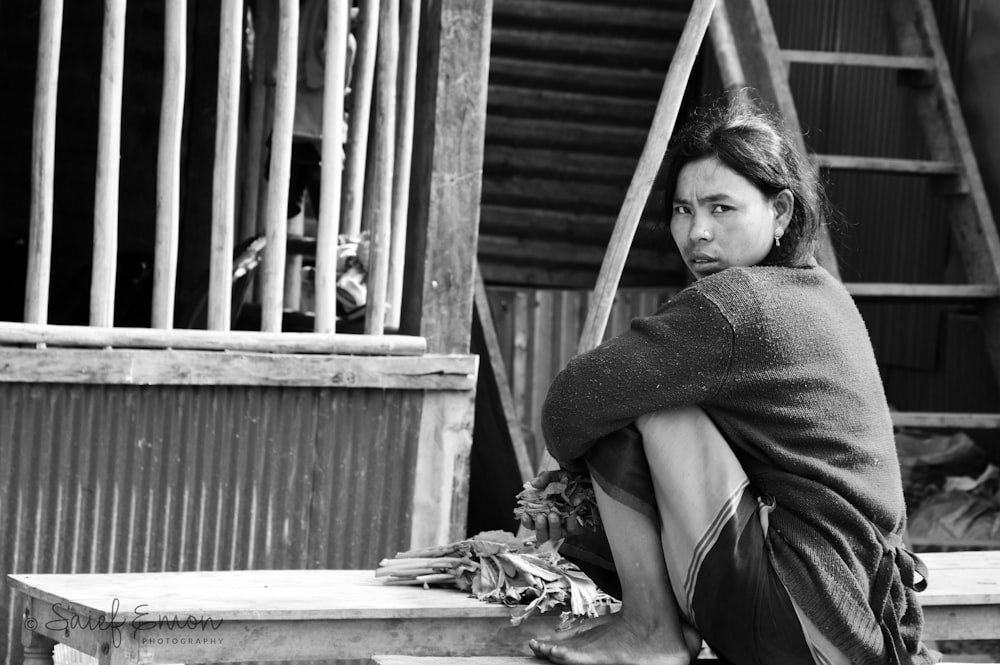 Frau im grauen Pullover sitzt auf einer Holztreppe