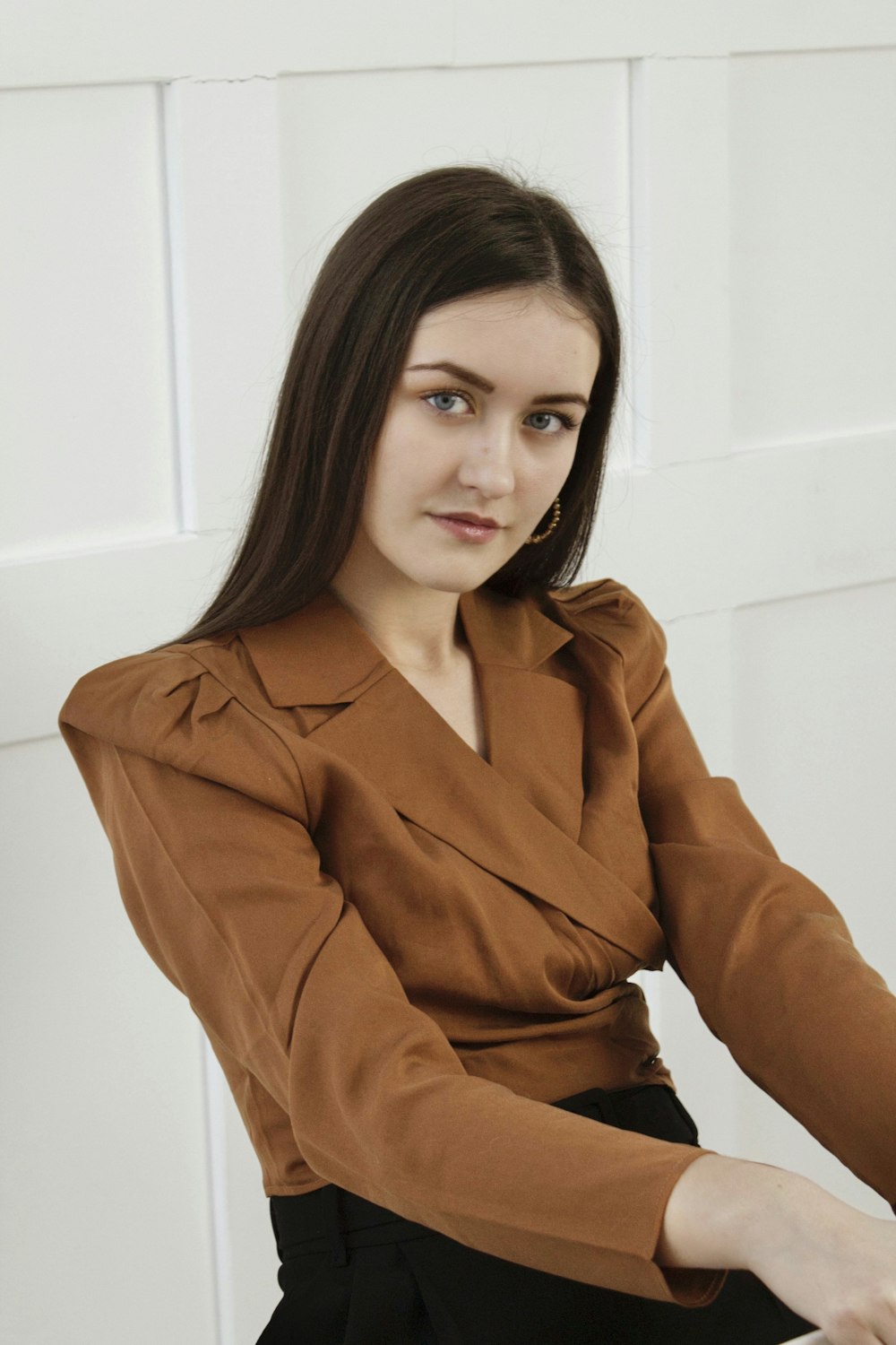 woman in brown coat standing near white wall